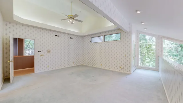 an empty room with windows and chandelier fan