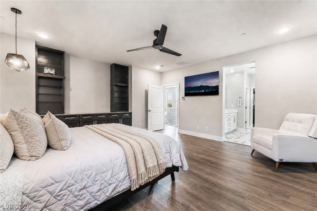 2166 Trivero Street Henderson, NV 89044 - Photo 26 of 61 Integrated shelving units frame the wall in this tranquil primary bedroom, complemented by warm wood flooring.