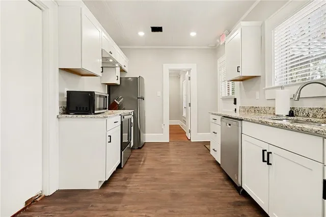 a kitchen with stainless steel appliances a stove top oven a sink a refrigerator white cabinets and a refrigerator