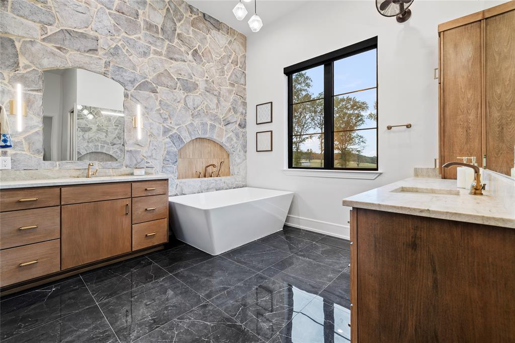 2804 Buchanan Road Hallsville, TX 75650 - Photo 16 of 40 a bathroom with a double vanity sink a mirror and a bathtub