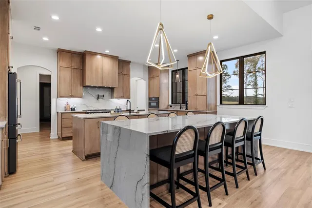 a kitchen with stainless steel appliances kitchen island granite countertop a table chairs sink and cabinets