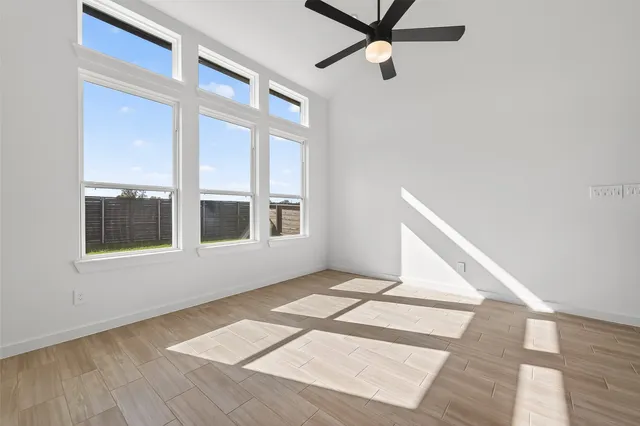 a view of an empty room with a window and wooden floor