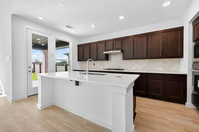 a kitchen with kitchen island granite countertop a sink and cabinets