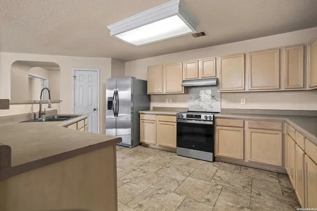 a kitchen with granite countertop a sink stove and refrigerator