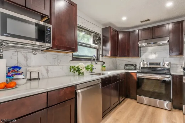 a kitchen with stainless steel appliances granite countertop a sink stove and microwave