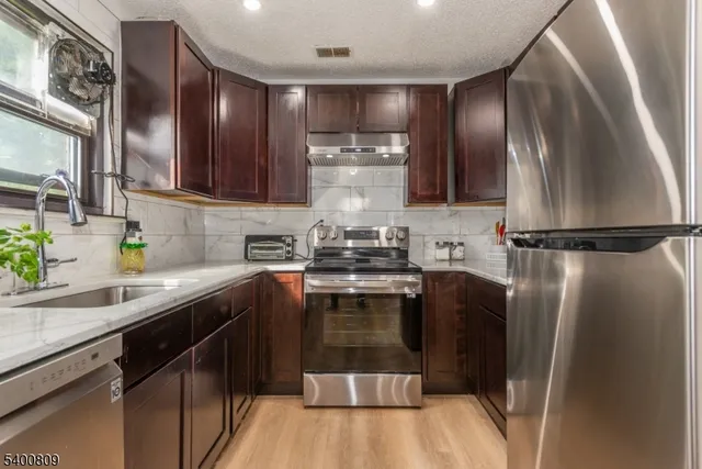 a kitchen with stainless steel appliances granite countertop a sink a stove and a refrigerator