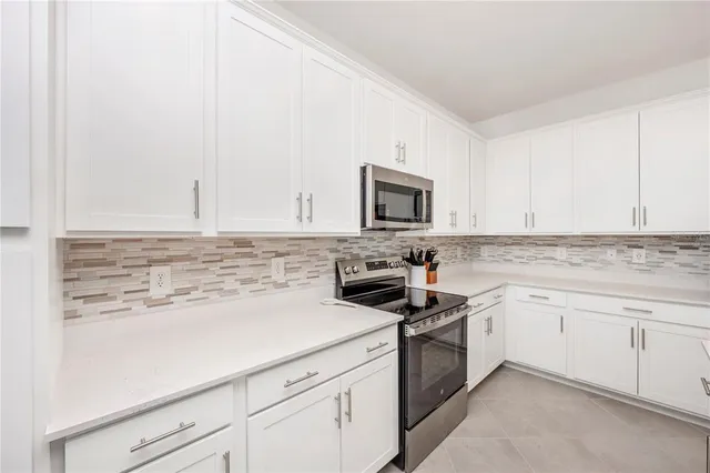 a living room with furniture kitchen view and a chandelier