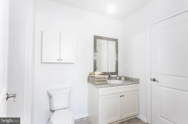 a bathroom with a granite countertop toilet and sink