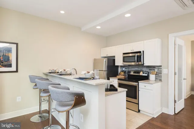 a kitchen with stainless steel appliances a stove top oven a sink a dining table and chairs