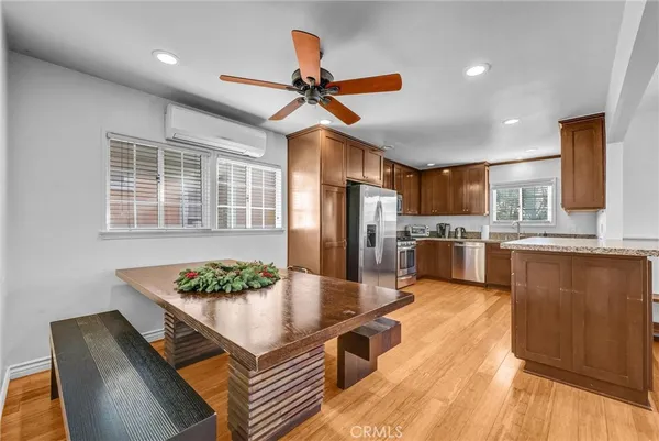a kitchen with stainless steel appliances granite countertop a refrigerator a stove a sink dishwasher a dining table and chairs with wooden floor