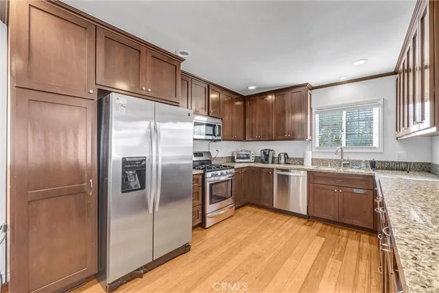 a kitchen with granite countertop stainless steel appliances a refrigerator a sink and cabinets