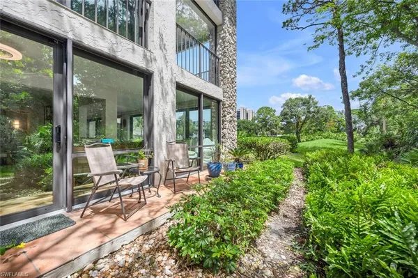 a view of a chair and tables in the patio next to a yard