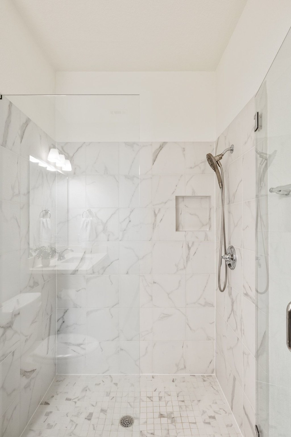 5812 Davenport Divide Road Austin, TX 78738 - Photo 30 of 40 Large format tile with subtle veining creates a seamless, high-end finish. A recessed niche keeps storage clean and integrated, and the frameless glass enclosure maintains openness in the space.