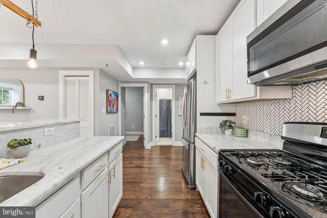 a large kitchen with stainless steel appliances granite countertop a lot of counter space and wooden floors