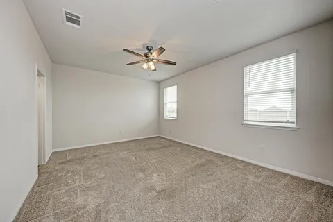 an empty room with windows and ceiling fan