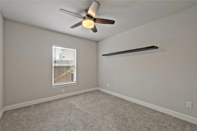 an empty room with window and ceiling fan