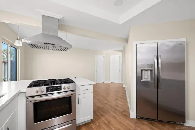 a kitchen with metallic refrigerator and wooden floor