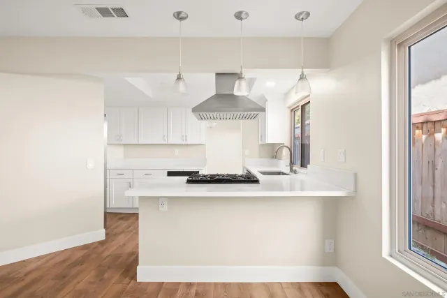 a large white kitchen with granite countertop a stove top oven a sink and dishwasher with wooden floor