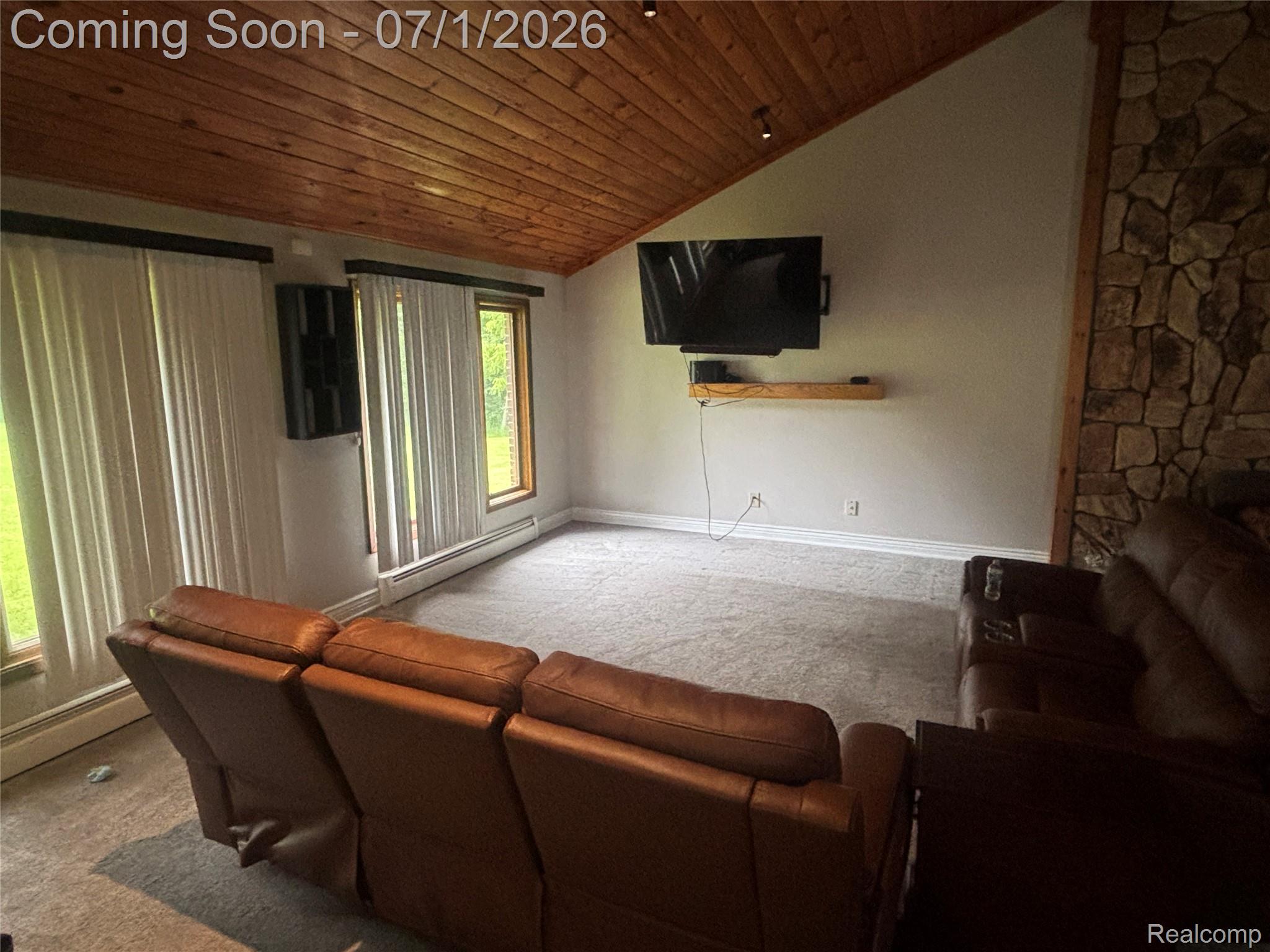 9844 Pine Knob Road Clarkston, MI 48348 - Photo 15 of 15 Living area featuring a wood-finish vaulted ceiling, a stone accent wall, and light-colored carpeting
