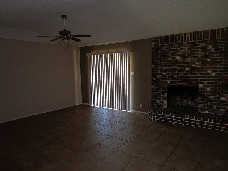 4004 Vicky Street Big Spring, TX 79720 - Photo 4 of 13 Living area featuring a brick fireplace with hearth, tile flooring, and a ceiling fan with integrated lighting