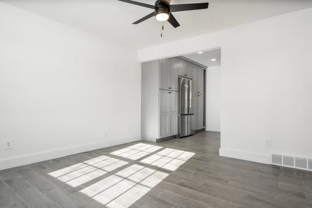 an empty room with wooden floor closet and windows