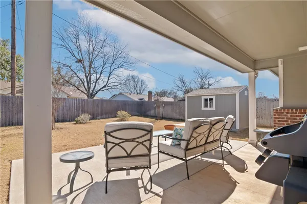 a patio with a table and chairs and potted plants