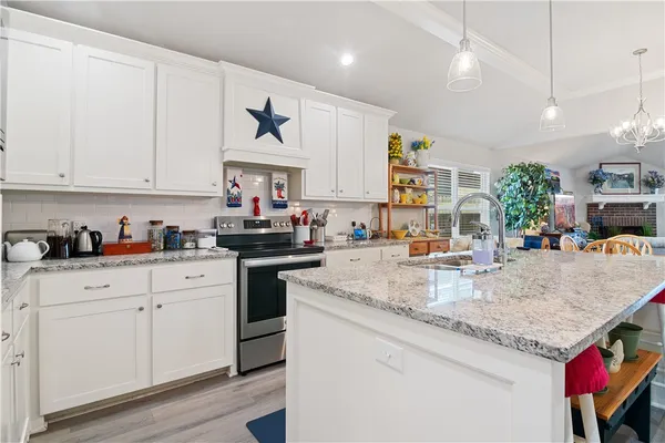 a kitchen with granite countertop a sink stainless steel appliances and white cabinets