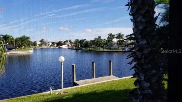 a view of a lake with a yard and table and chairs under an umbrella