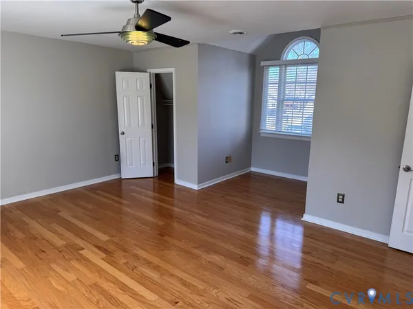 a view of an empty room with closet and wooden floor