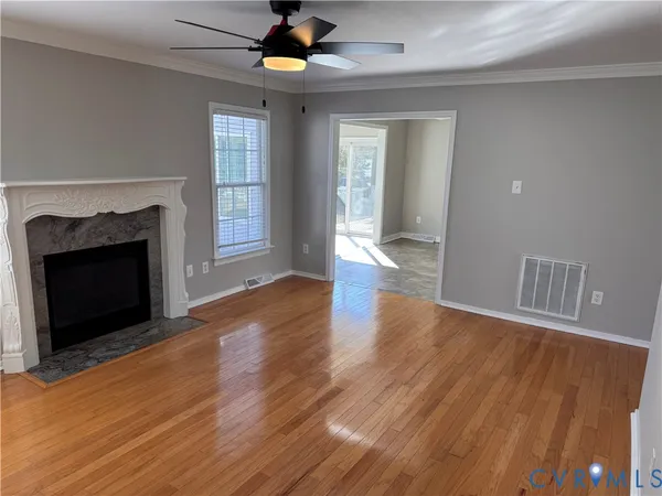 an empty room with wooden floor fan and windows