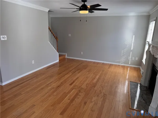 an empty room with wooden floor fireplace and windows