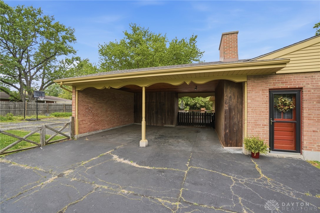 6119 Flemington Road Dayton, OH 45459 - Photo 68 of 76 This residence features a convenient carport and a classic brick facade with a charming red door.