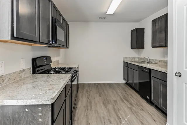 a kitchen with stainless steel appliances granite countertop a sink stove and microwave