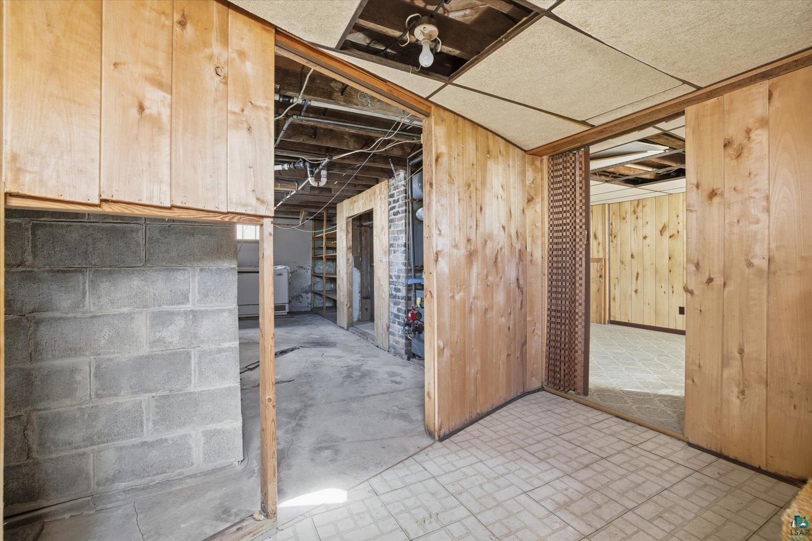 709 Michigan Street Hibbing, MN 55746 - Photo 39 of 47 Unfinished basement featuring wooden walls and brick patterned floors
