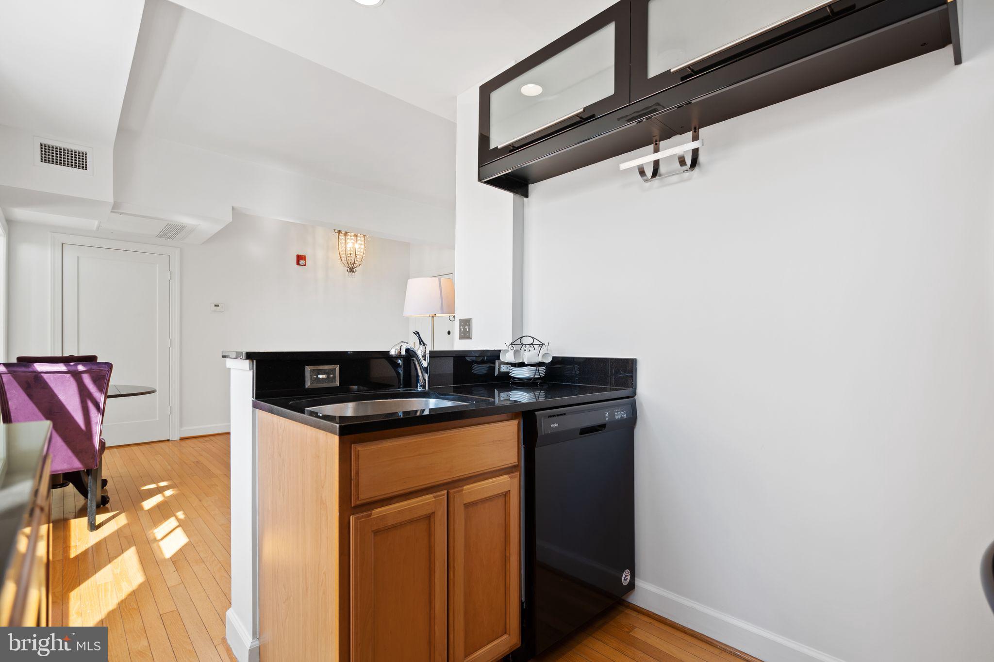 2902 Porter Street Northwest, Unit 43 Washington, DC 20008 - Photo 13 of 31 a kitchen with granite countertop a sink cabinets and a wooden floor
