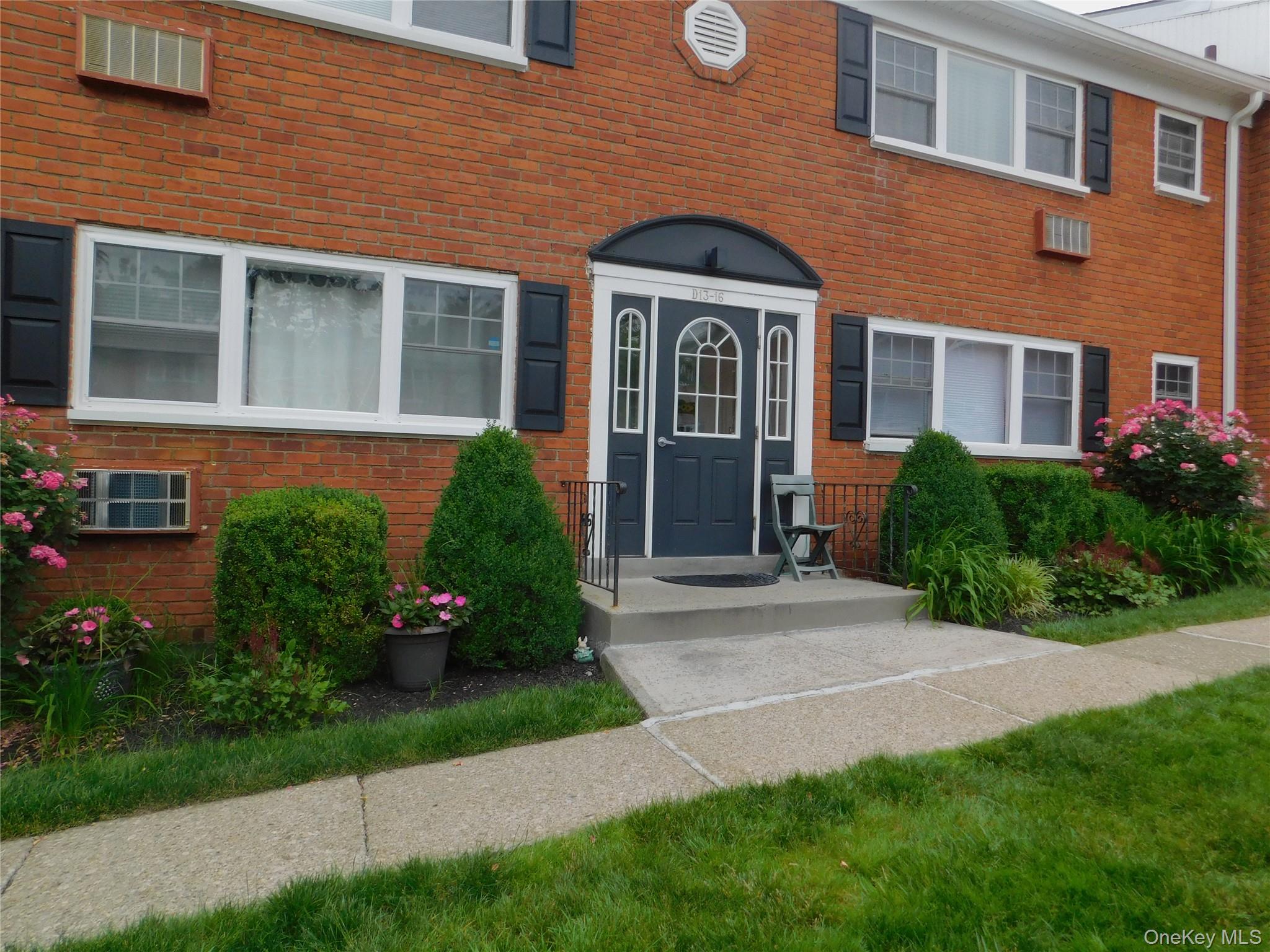 a front view of a house with a yard and potted plants