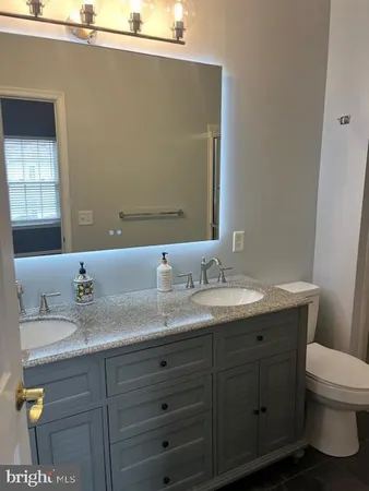 a bathroom with a granite countertop sink a toilet and a mirror
