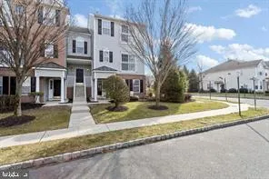 a view of a white house with a yard next to a road