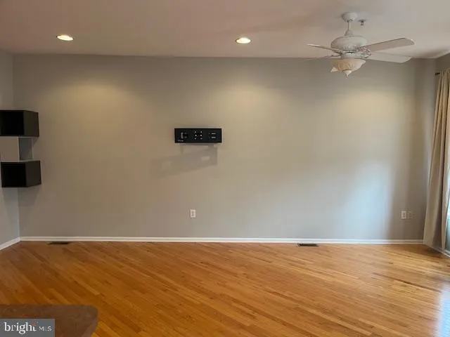 an empty room with wooden floor and fan