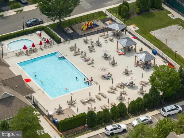 an aerial view of a tennis ground and a cars park side of the road