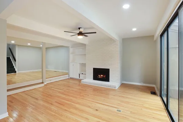 a view of an empty room with wooden floor and a ceiling fan