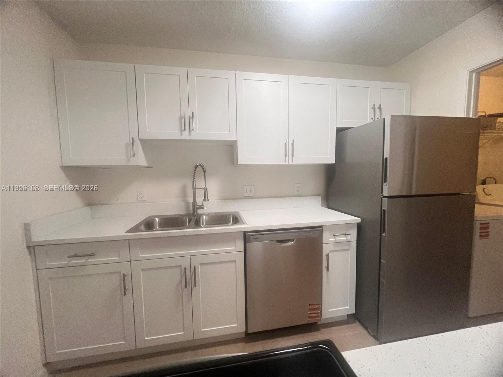 a kitchen with white cabinets and refrigerator