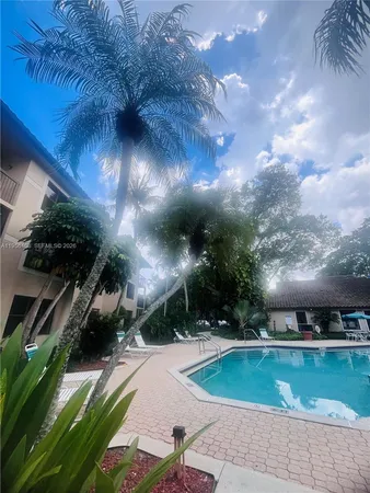 a view of a swimming pool with lawn chairs under an umbrella