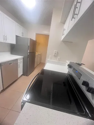 a kitchen with a refrigerator and white cabinets