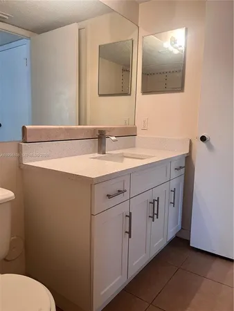 a bathroom with a granite countertop sink mirror and toilet