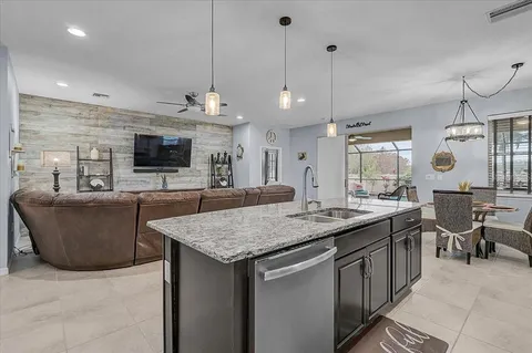 a kitchen with kitchen island granite countertop a sink a counter top space appliances and cabinets