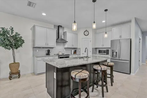 a kitchen with stainless steel appliances granite countertop a sink a stove a refrigerator and island with wooden floor