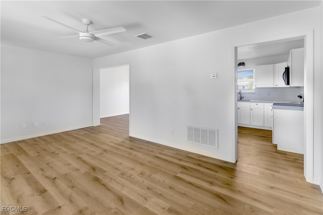 10697 Holly Road Bokeelia, FL 33922 - Photo 19 of 50 an empty room with wooden floor and a kitchen space with a sink