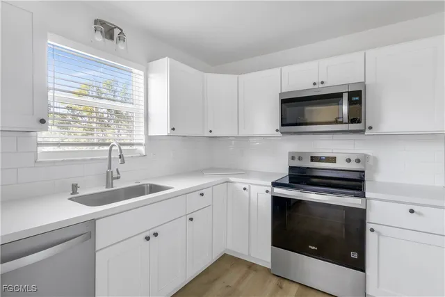 a kitchen with white cabinets appliances and a sink