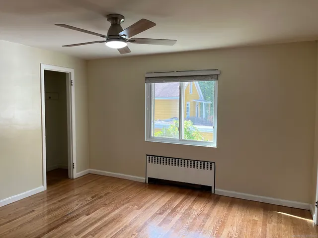 an empty room with wooden floor cabinet and windows